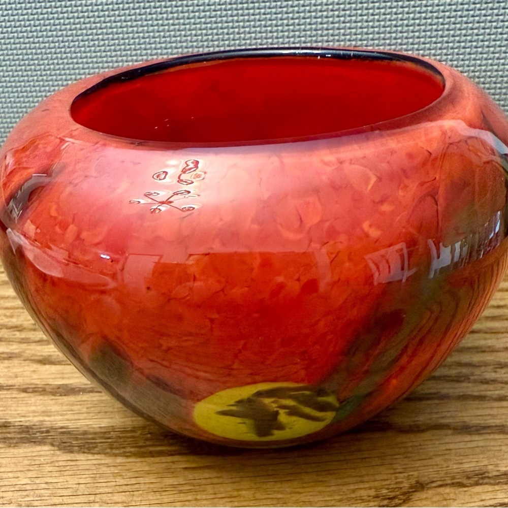 handmade studio art red glass bowl with a mottled design and a maker's mark.